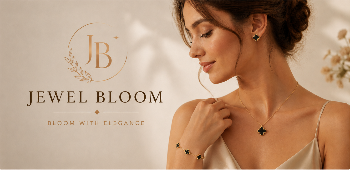 A woman in a satin slip dress models jewelry from Jewel Bloom, including a gold necklace with a black clover pendant, matching stud earrings, and a bracelet, set against a warm beige background with the brand logo.